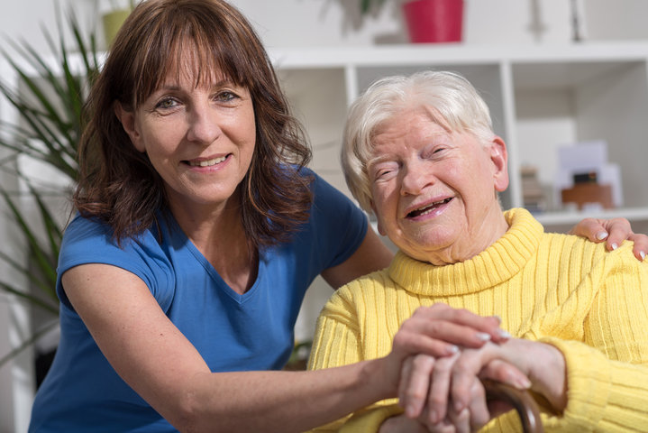 mother and daughter sat side by side smiling in care home