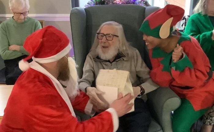 santa and a elf giving a resident a present