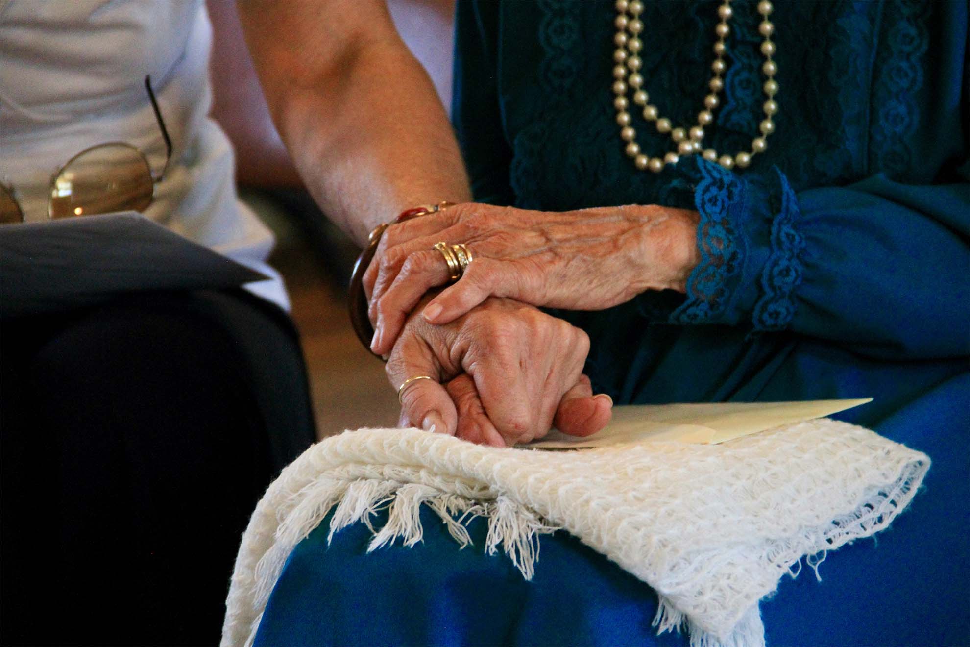 Staff member holding hands with an elderly resident to comfort them