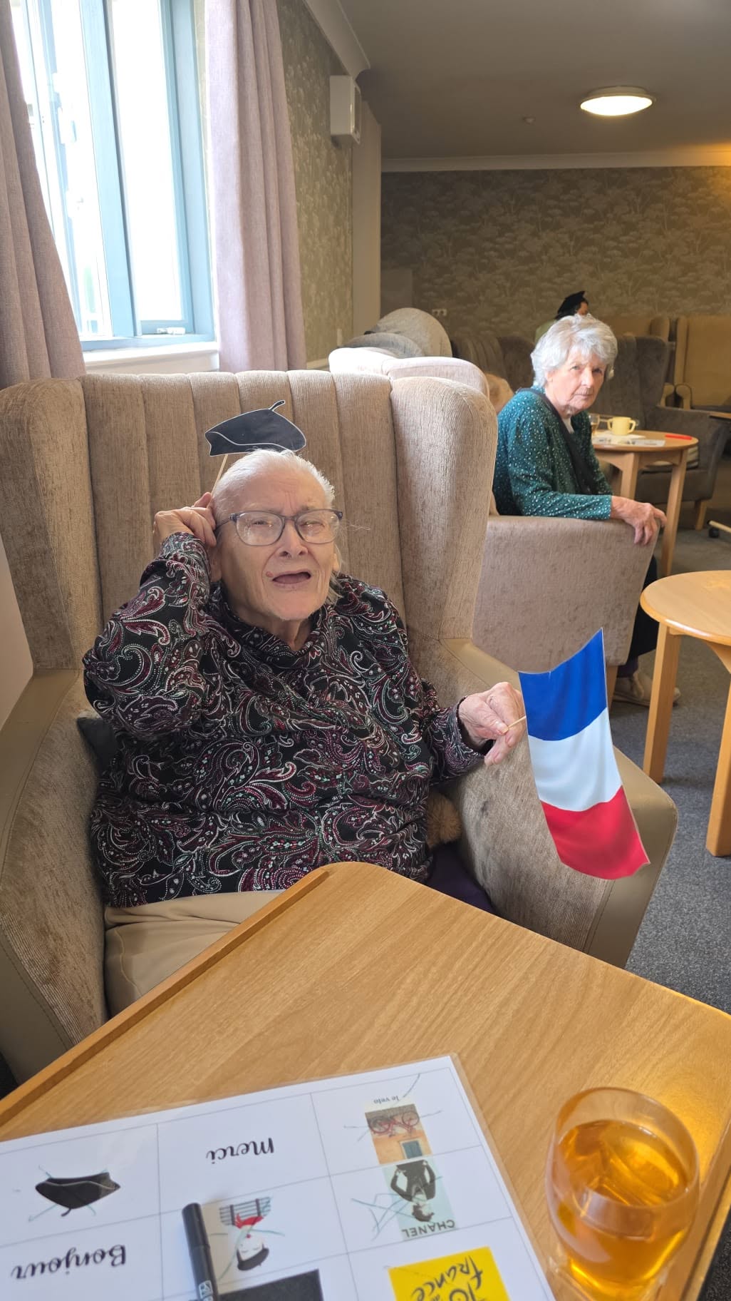 an older lady sat in a chair holding a french flag