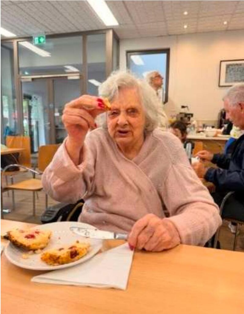 elderly woman enjoying a scone in a garden centre cafe