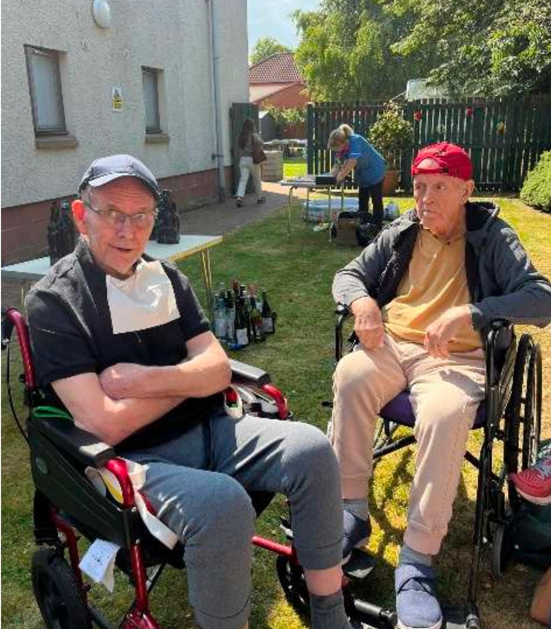 two male residents sat in garden sunshine
